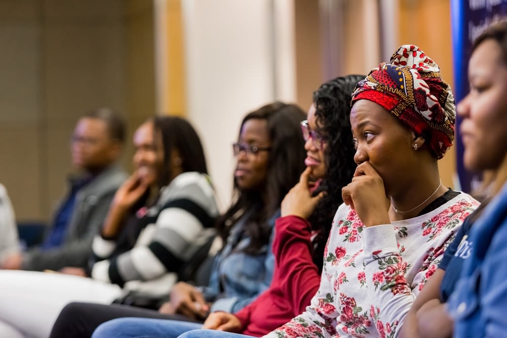 A couple of women standing next to each other with laptops