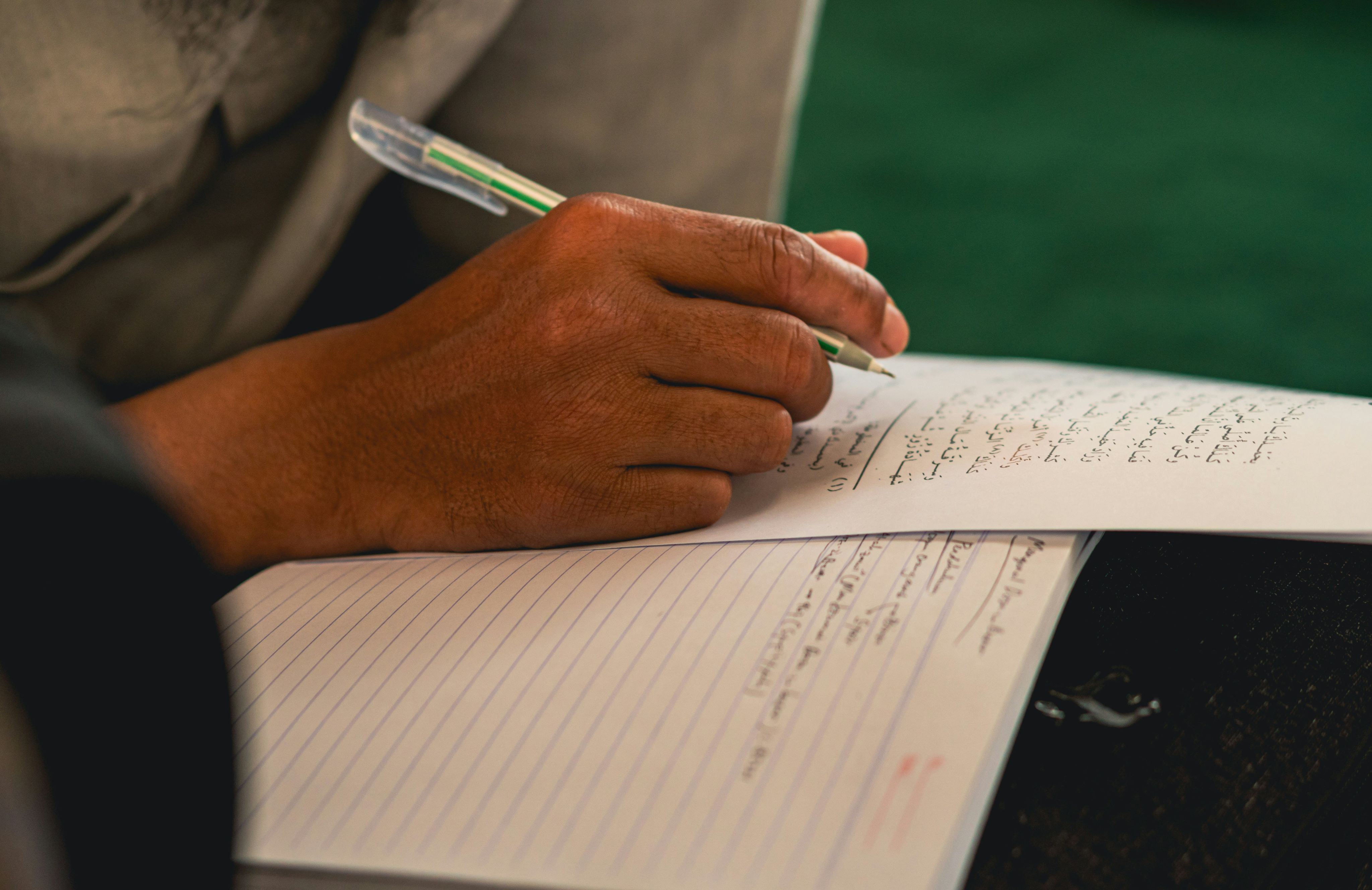 A person writing on a notebook with a pen